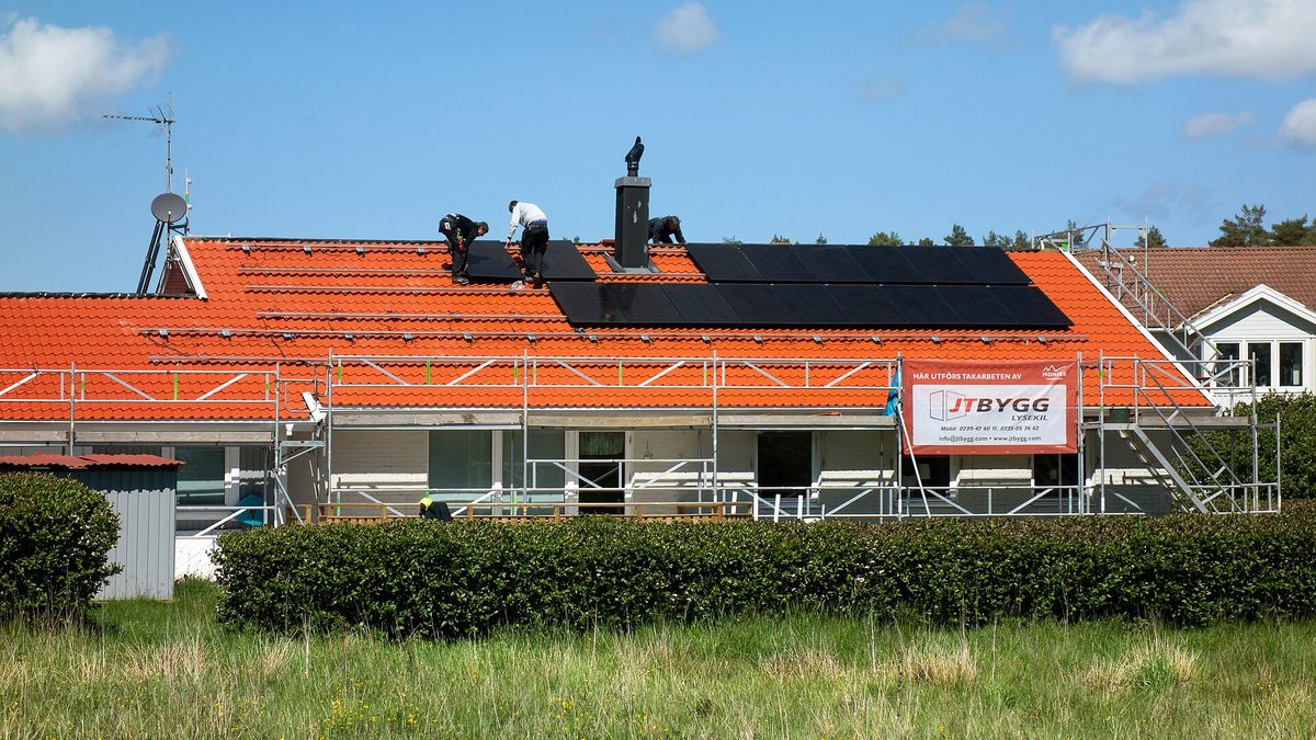 Tre montörer installerar solpaneler på ett hustak